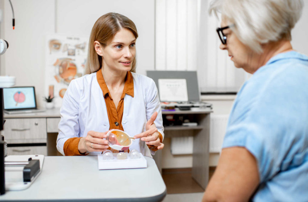 A young female eye doctor explaining the findings of the Optomap exam to her patient, and pointing to a diagram of a cross-section of the eye.