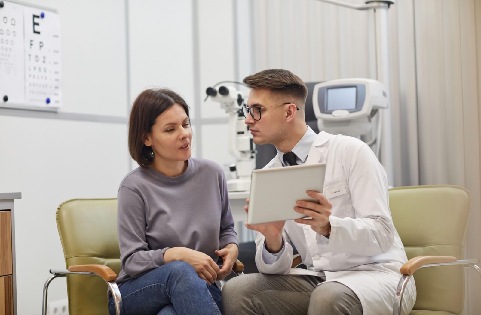 A patient listening attentively to her optometrist who is showing his findings.