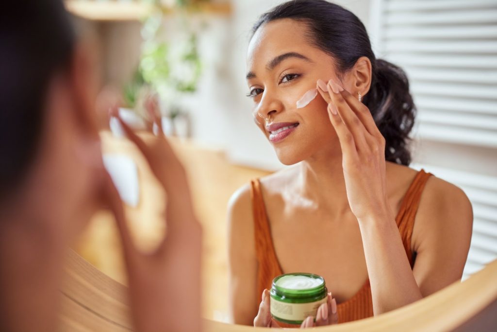 A woman applying face cream.