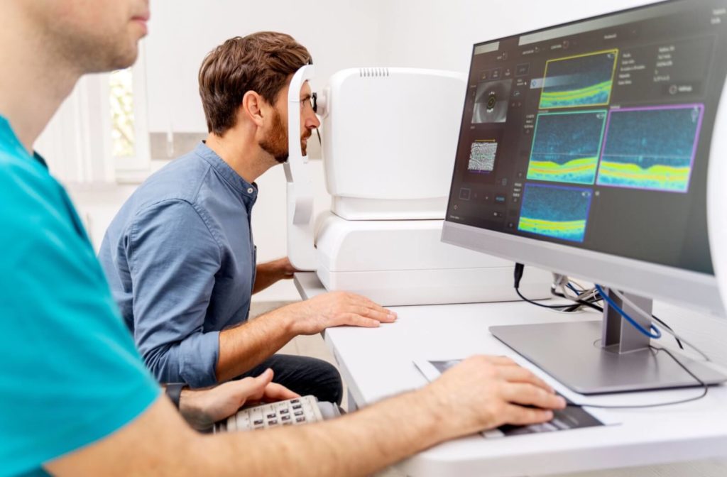 Young man visiting his ophthalmologist, doctor working with computer.