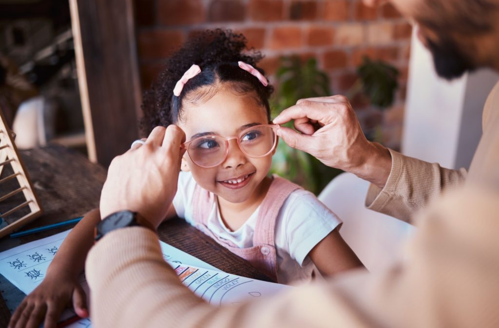 An optometrist helps a child with their glasses.