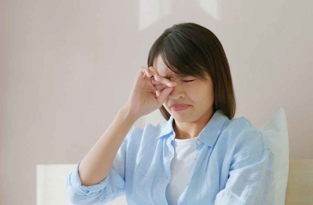 A person struggling with dry eyes rubbing their irritated eyes.