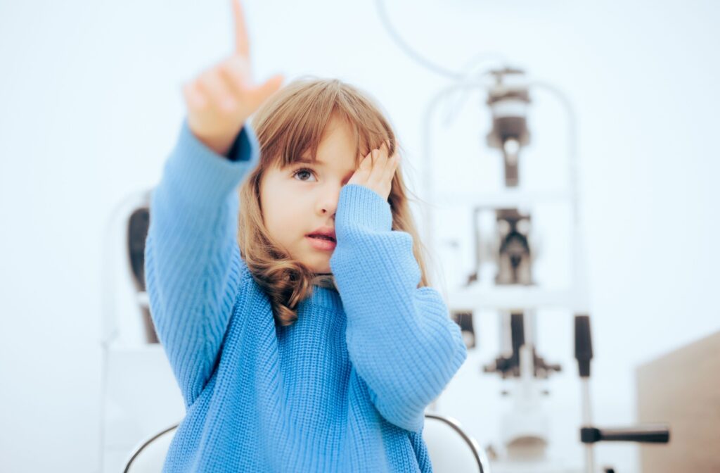 Young girl covering one eye while pointing at a distance, illustrating a vision test for myopia.