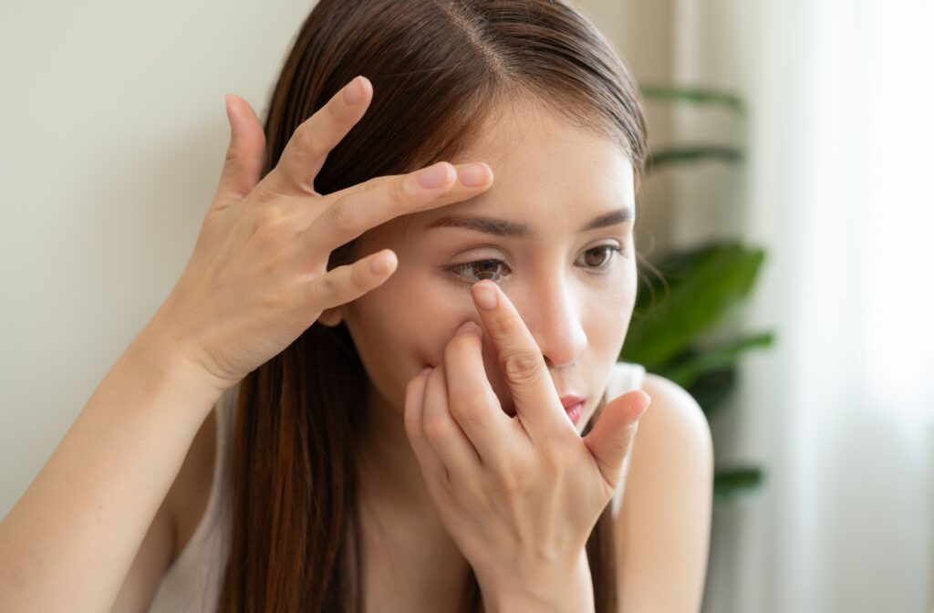 Woman inserting a multifocal contact lens into her eye at home.
