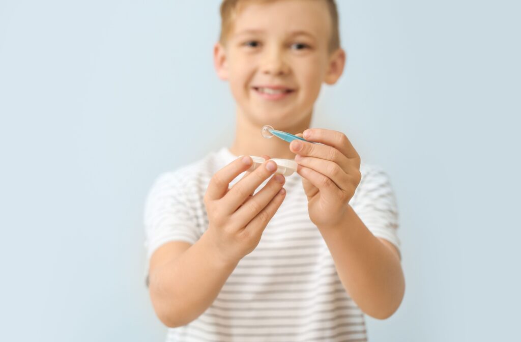Young boy at Southwood Eyecare holding a contact lens case and tweezers, learning how to care for contact lenses during a fitting.