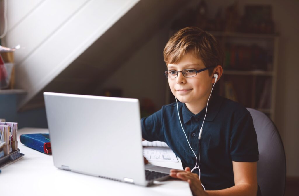 School-age girl in spectacles reading a book, illustrating eye-friendly habits during homework.