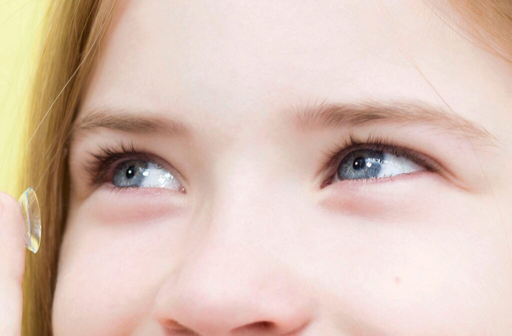 School-age girl at Southwood Eyecare inserting a contact lens while looking into a mirror, showing safe lens use for children.