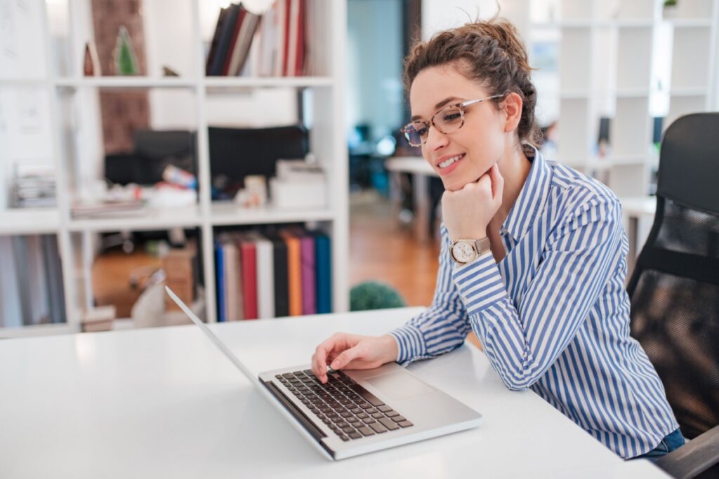 Woman wearing prescription glasses comfortably working on laptop with clear vision in office setting.